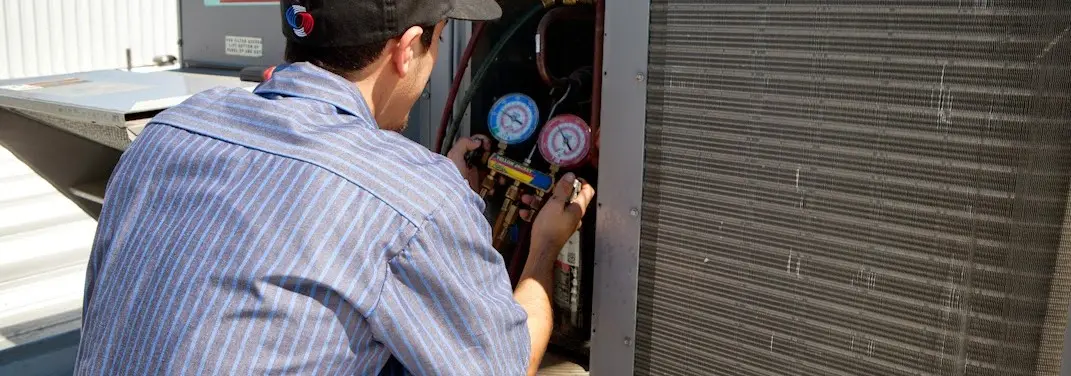 HVAC technician servicing a condenser unit in Herriman
